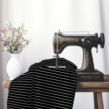 Black Cotton Sateen Fabric with Fine White Stripes, FACS-1010-152, on an antique sewing machine sitting on a desk with vase of beautiful flowers.