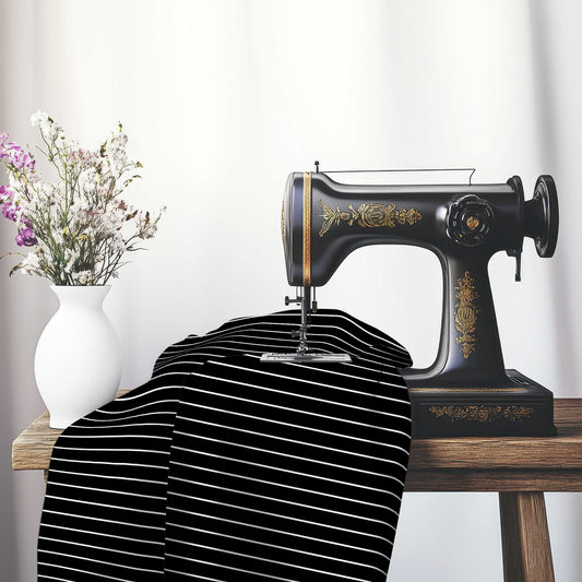Black Cotton Sateen Fabric with Fine White Stripes, FACS-1010-152, on an antique sewing machine sitting on a desk with vase of beautiful flowers.