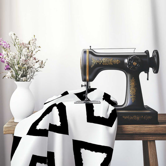 Off-White Cotton Sateen Fabric with Bold Black Graphic , FASC-1010-391, on an antique sewing machine sitting on a desk with vase of beautiful flowers.