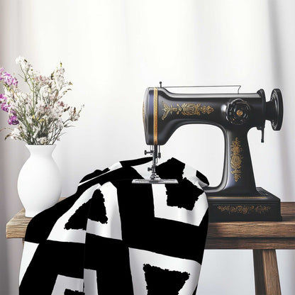 Black Cotton Sateen Fabric with Bold Off-White Graphic , FASC-1010-392, on an antique sewing machine sitting on a desk with vase of beautiful flowers.