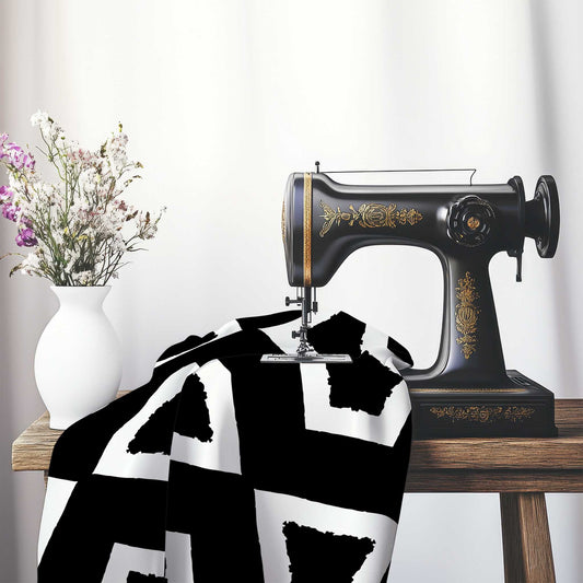 Black Cotton Sateen Fabric with Bold Off-White Graphic , FASC-1010-392, on an antique sewing machine sitting on a desk with vase of beautiful flowers.