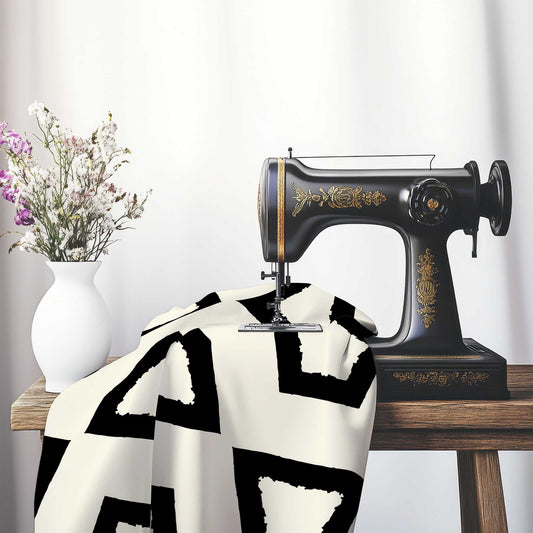 Pale Cream Cotton Sateen Fabric with Bold Black Graphic , FASC-1013-391, on an antique sewing machine sitting on a desk with vase of beautiful flowers.