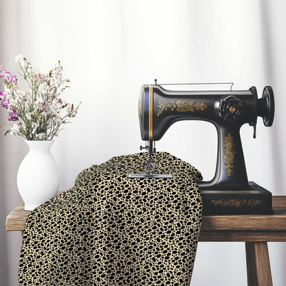 Tan Cotton Sateen Fabric with Black Hand-painted Dab Motif Print, FASC-1014-092, on an antique sewing machine sitting on a desk with vase of beautiful flowers.