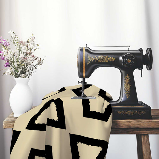 Tan Cotton Sateen Fabric with Bold Black Graphic , FASC-1014-391, on an antique sewing machine sitting on a desk with vase of beautiful flowers.