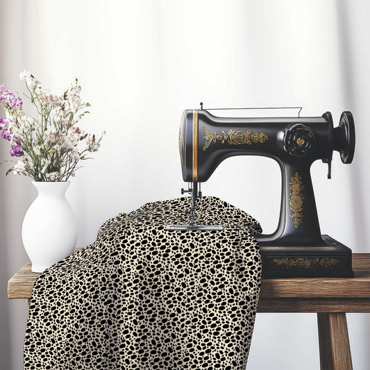 Beige Cotton Sateen Fabric with Black Hand-painted Dab Motif Print, FASC-1015-092, on an antique sewing machine sitting on a desk with vase of beautiful flowers.