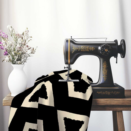 Black Cotton Sateen Fabric with Bold Beige Graphic , FASC-1015-392, on an antique sewing machine sitting on a desk with vase of beautiful flowers.
