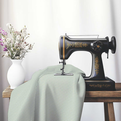 Off-White Cotton Sateen Fabric with Green Double Weave Motif Print, FASC-1052-144, on an antique sewing machine sitting on a desk with vase of beautiful flowers.