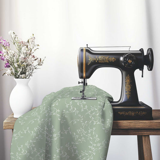 Green Cotton Sateen Fabric with Off-White Vine Print , FASC-1052-182, on an antique sewing machine sitting on a desk with vase of beautiful flowers.