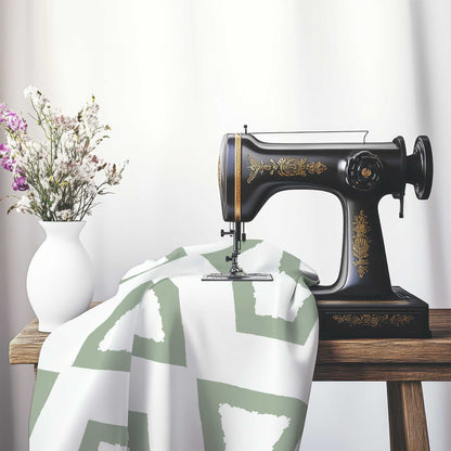 Off-White Cotton Sateen Fabric with Bold Green Graphic , FASC-1052-391, on an antique sewing machine sitting on a desk with vase of beautiful flowers.