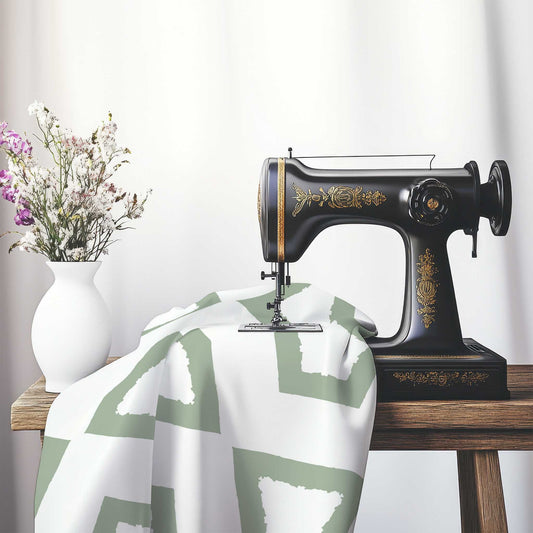 Off-White Cotton Sateen Fabric with Bold Green Graphic , FASC-1052-391, on an antique sewing machine sitting on a desk with vase of beautiful flowers.