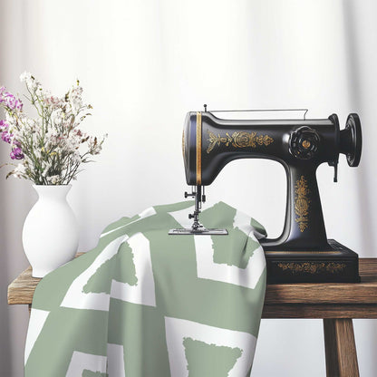 Green Cotton Sateen Fabric with Bold Off-White Graphic , FASC-1052-392, on an antique sewing machine sitting on a desk with vase of beautiful flowers.