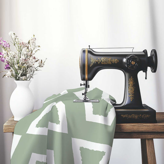 Green Cotton Sateen Fabric with Bold Off-White Graphic , FASC-1052-392, on an antique sewing machine sitting on a desk with vase of beautiful flowers.