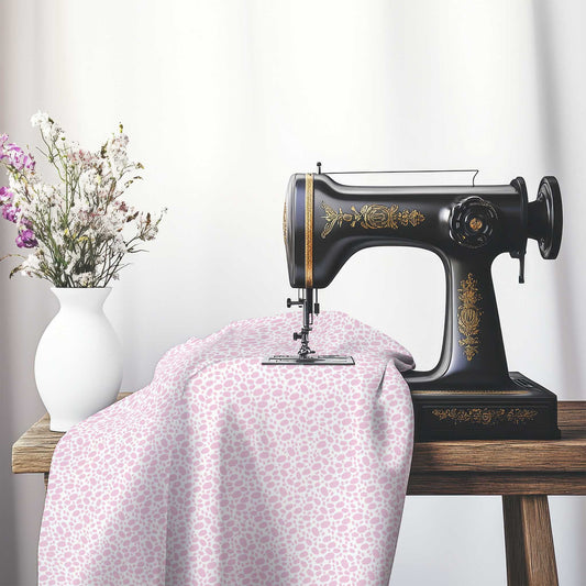 Off-White Cotton Sateen Fabric with Pink Hand-painted Dab Motif Print, FASC-1081-092, on an antique sewing machine sitting on a desk with vase of beautiful flowers.