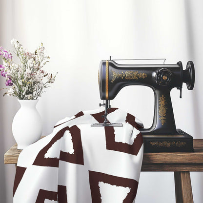 Off-White Cotton Sateen Fabric with Bold Brown Graphic , FASC-1161-391, on an antique sewing machine sitting on a desk with vase of beautiful flowers.