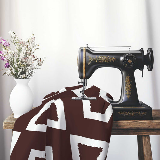Brown Cotton Sateen Fabric with Bold Off-White Graphic , FASC-1161-392, on an antique sewing machine sitting on a desk with vase of beautiful flowers.