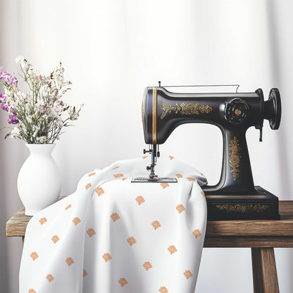 Off-White Cotton Sateen Fabric with Orange Hand-painted Swizzle Motif Print, FASC-1181-171, on an antique sewing machine sitting on a desk with vase of beautiful flowers.