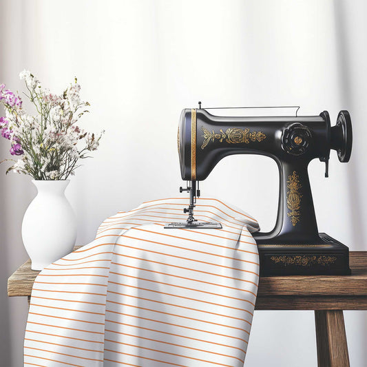 White Cotton Sateen Fabric with Fine Orange Stripes, FACS-1181-151, on an antique sewing machine sitting on a desk with vase of beautiful flowers.
