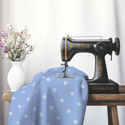Blue Cotton Sateen Fabric with Off-White Hand-painted Swizzle Motif Print, FASC-1231-172, on an antique sewing machine sitting on a desk with vase of beautiful flowers.