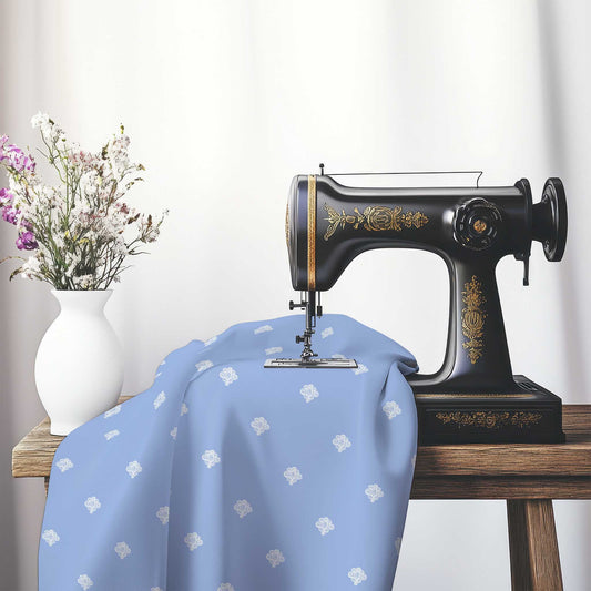 Blue Cotton Sateen Fabric with Off-White Hand-painted Swizzle Motif Print, FASC-1231-172, on an antique sewing machine sitting on a desk with vase of beautiful flowers.