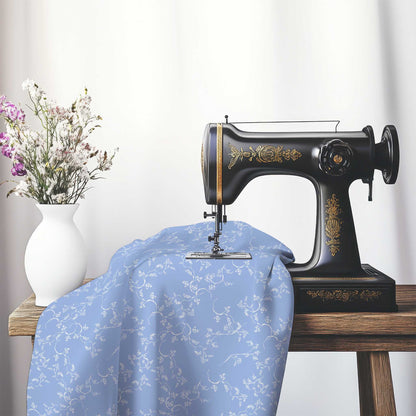 Blue Cotton Sateen Fabric with Off-White Vine Print , FASC-1231-182, on an antique sewing machine sitting on a desk with vase of beautiful flowers.