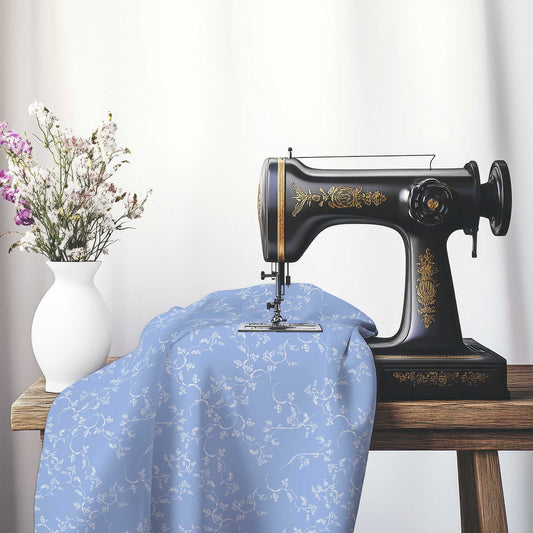 Blue Cotton Sateen Fabric with Off-White Vine Print , FASC-1231-182, on an antique sewing machine sitting on a desk with vase of beautiful flowers.