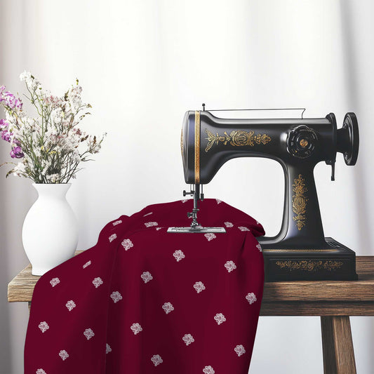 Burgundy Red Cotton Sateen Fabric with Off-White Hand-painted Swizzle Motif Print, FASC-1281-172, on an antique sewing machine sitting on a desk with vase of beautiful flowers.