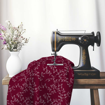Burgundy Red Cotton Sateen Fabric with Off-White Vine Print , FASC-1281-182, on an antique sewing machine sitting on a desk with vase of beautiful flowers.