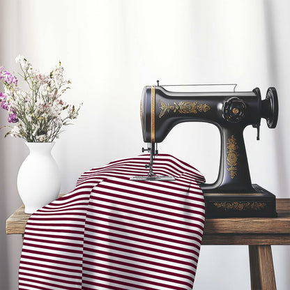White Cotton Sateen Fabric with Thin Burgundy Red Bars, FACS-1281-241, on an antique sewing machine sitting on a desk with vase of beautiful flowers.