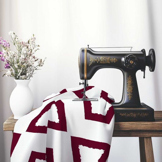 Off-White Cotton Sateen Fabric with Bold Burgundy Red Graphic , FASC-1281-391, on an antique sewing machine sitting on a desk with vase of beautiful flowers.