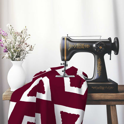 Burgundy Red Cotton Sateen Fabric with Bold Off-White Graphic , FASC-1281-392, on an antique sewing machine sitting on a desk with vase of beautiful flowers.
