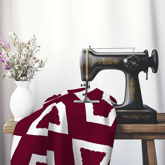 Burgundy Red Cotton Sateen Fabric with Bold Off-White Graphic , FASC-1281-392, on an antique sewing machine sitting on a desk with vase of beautiful flowers.