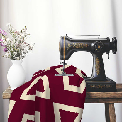 Burgundy Red Cotton Sateen Fabric with Bold Beige Graphic , FASC-1285-392, on an antique sewing machine sitting on a desk with vase of beautiful flowers.