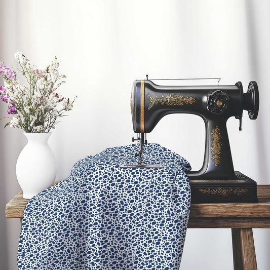 Off-White Cotton Sateen Fabric with Royal Blue Hand-painted Dab Motif Print, FASC-1291-092, on an antique sewing machine sitting on a desk with vase of beautiful flowers.