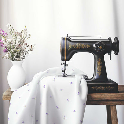 Printed Fabric with Handpainted Small Purple Watercolor Floral Pattern, FACS-1326, on an antique sewing machine sitting on a desk with vase of beautiful flowers.