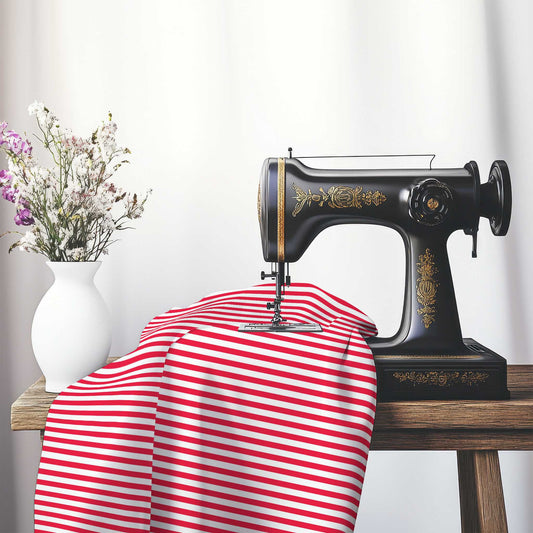 White Cotton Sateen Fabric with Thin Red Bars, FACS-1330-241, on an antique sewing machine sitting on a desk with vase of beautiful flowers.