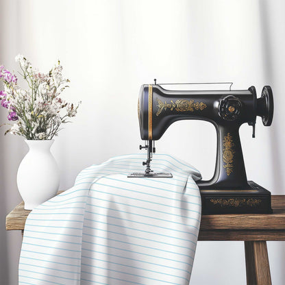 White Cotton Sateen Fabric with Fine Blue Stripes, FACS-1370-151, on an antique sewing machine sitting on a desk with vase of beautiful flowers.