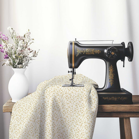 Off-White Cotton Sateen Fabric with Tan Hand-painted Dab Motif Print, FASC-1371-092, on an antique sewing machine sitting on a desk with vase of beautiful flowers.
