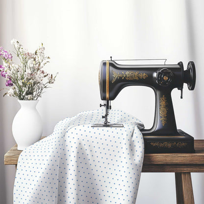 White Cotton Sateen Fabric with Fine Blue Diamonds, FACS-1400-111, on an antique sewing machine sitting on a desk with vase of beautiful flowers.
