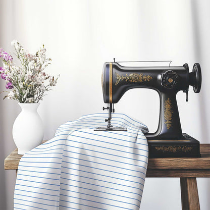 White Cotton Sateen Fabric with Fine Blue Stripes, FACS-1400-151, on an antique sewing machine sitting on a desk with vase of beautiful flowers.