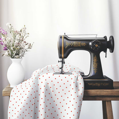 White Cotton Sateen Fabric with Red Diamonds, FACS-1410-101, on an antique sewing machine sitting on a desk with vase of beautiful flowers.