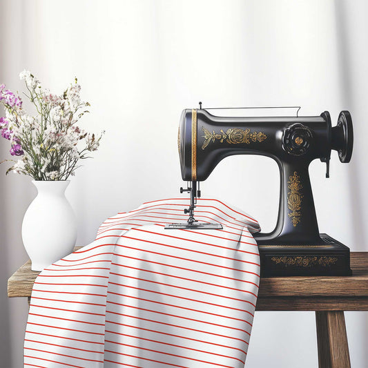 White Cotton Sateen Fabric with Fine Red Stripes, FACS-1410-151, on an antique sewing machine sitting on a desk with vase of beautiful flowers.
