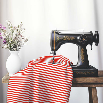 White Cotton Sateen Fabric with Thin Red Bars, FACS-1410-241, on an antique sewing machine sitting on a desk with vase of beautiful flowers.