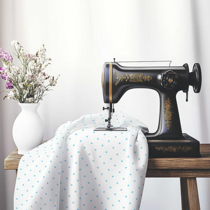 White Cotton Sateen Fabric with Blue Diamonds, FACS-1430-101, on an antique sewing machine sitting on a desk with vase of beautiful flowers.
