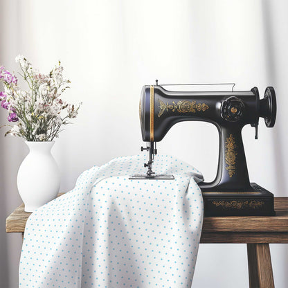White Cotton Sateen Fabric with Fine Blue Diamonds, FACS-1430-111, on an antique sewing machine sitting on a desk with vase of beautiful flowers.