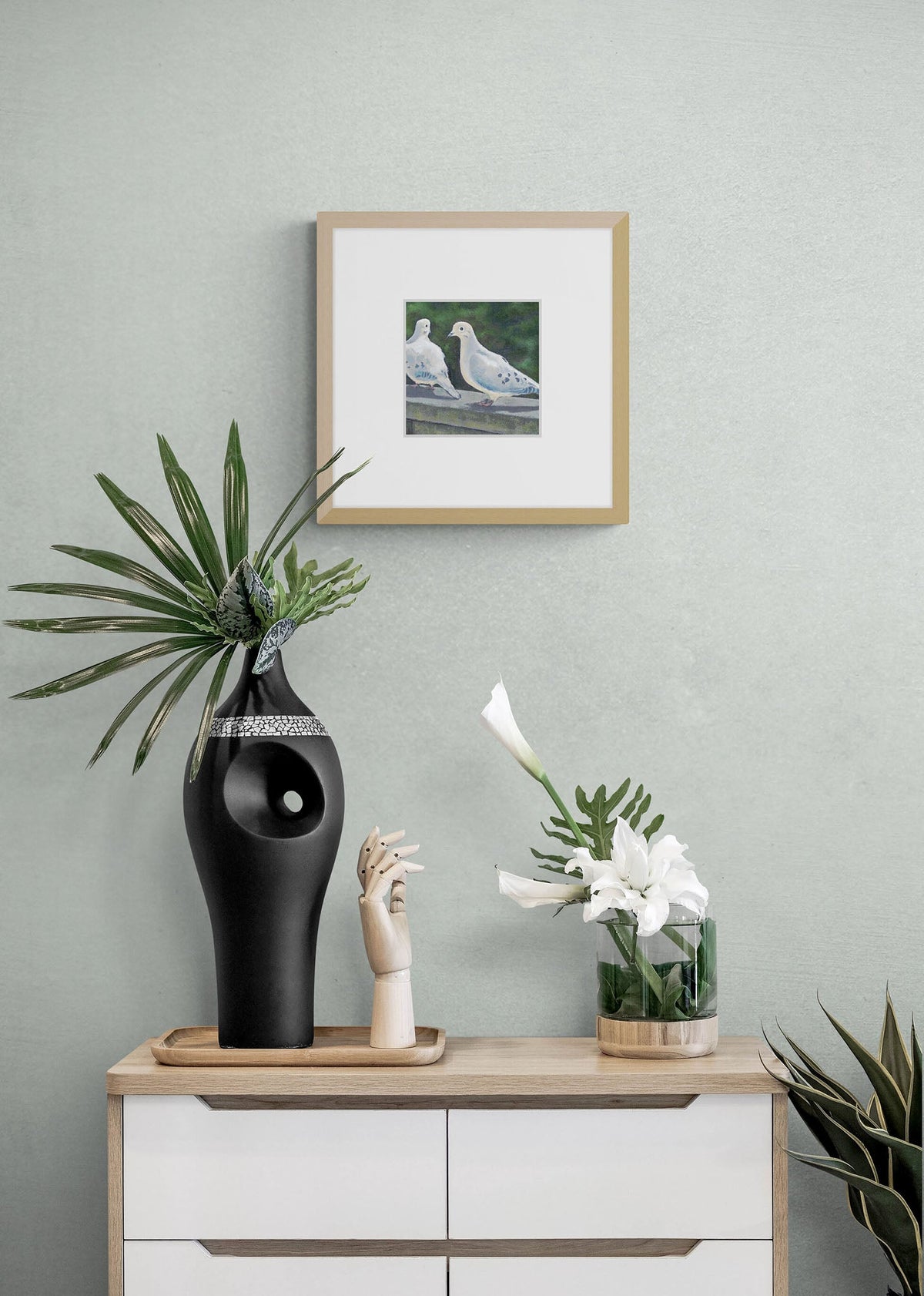 Mourning Doves Fine Art Print with Faux Mat Board | Styled in Serene Sage Green Vignette with Oak Dresser, Sculptural Black Ceramic Vase, Wooden Hand Figure and White Calla Lily Stems